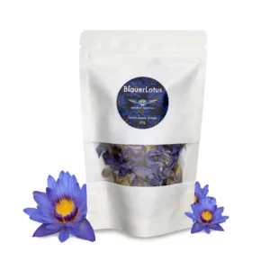 Weiße Verpackung mit Sichtfenster, die getrocknete Blauer-Lotus-Blüten enthält. Vor der Packung liegen dekorativ mehrere frische blaue Lotusblüten