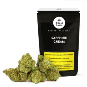 Qualicann Sapphire Cream CBD-Blüten vor schwarzer Verpackung mit mehreren hellgrünen, harzigen Cannabisbuds auf hellem Hintergrund