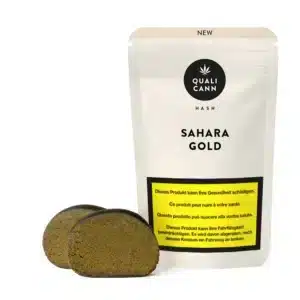 Qualicann Sahara Gold CBD-Hash mit zwei goldbraunen Hash-Blöcken vor der passenden Verpackung auf hellem Hintergrund